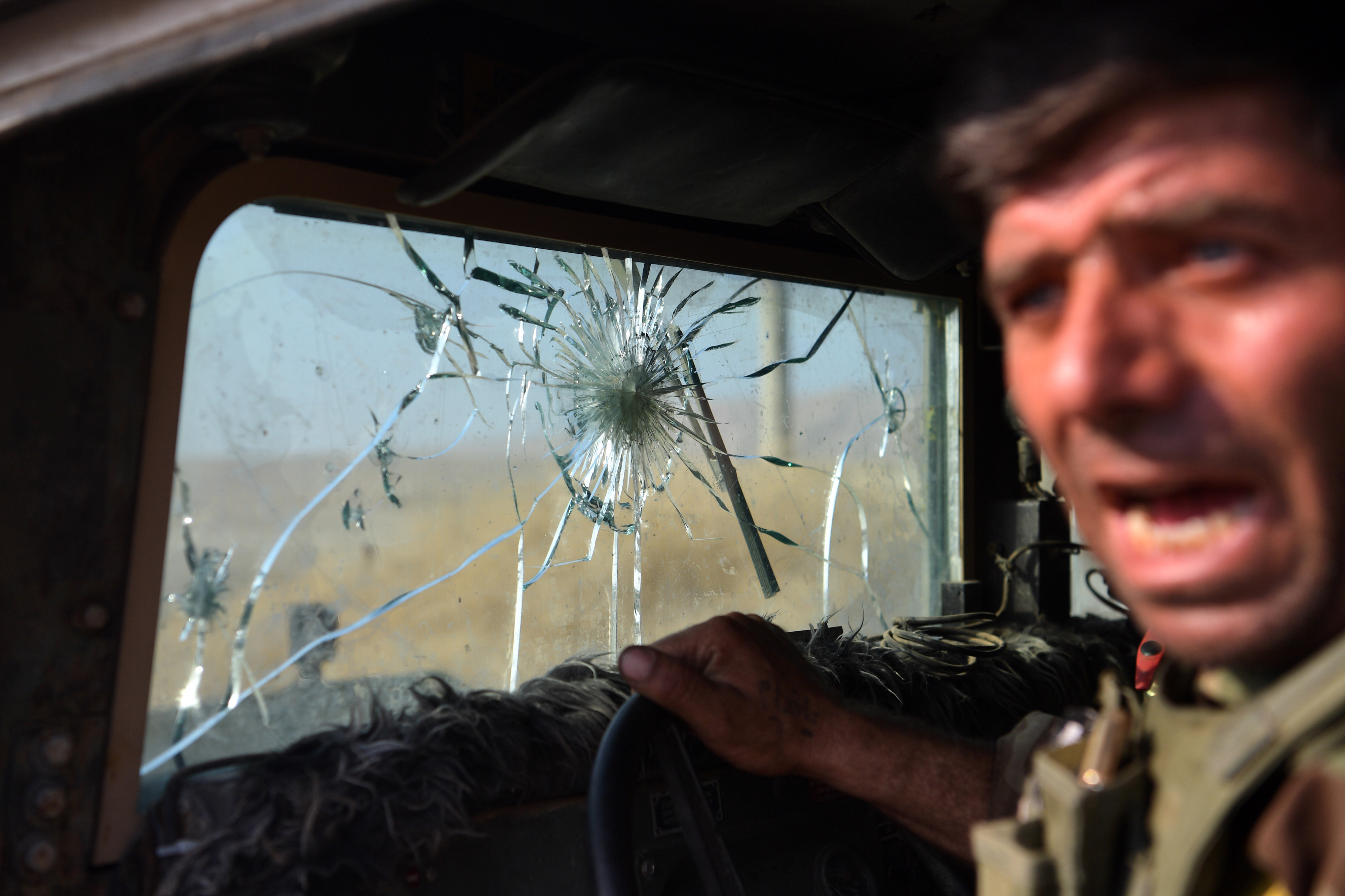 A Kurdish Peshmerga fighter reacts to hits against his vehicle from Islamic State snipers located in the small town of Bartella just outside Mosul. 