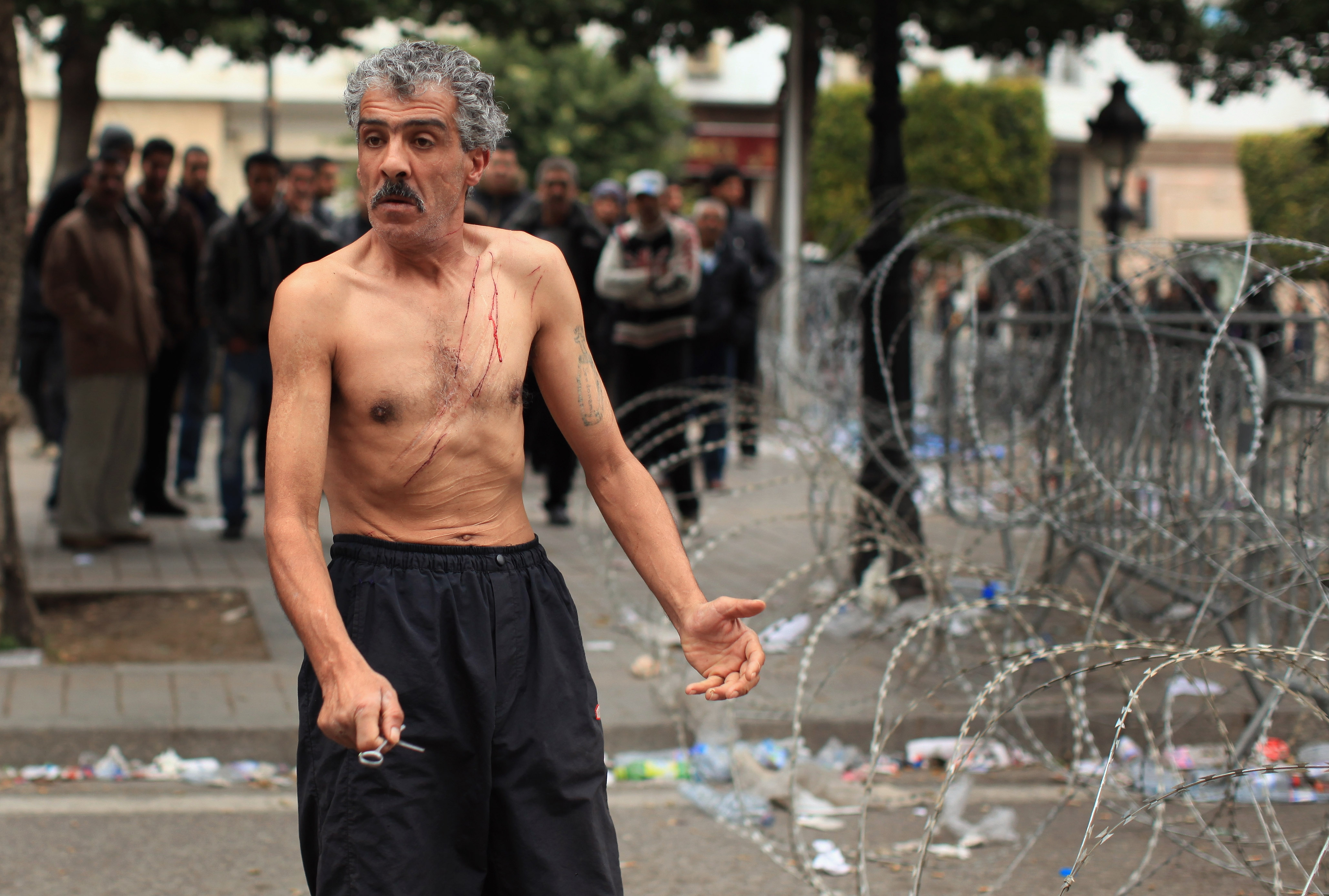 A man cuts himself with scissors during protests on Jan. 25 outside the Tunisian Interior Ministry in the government square in Tunis.