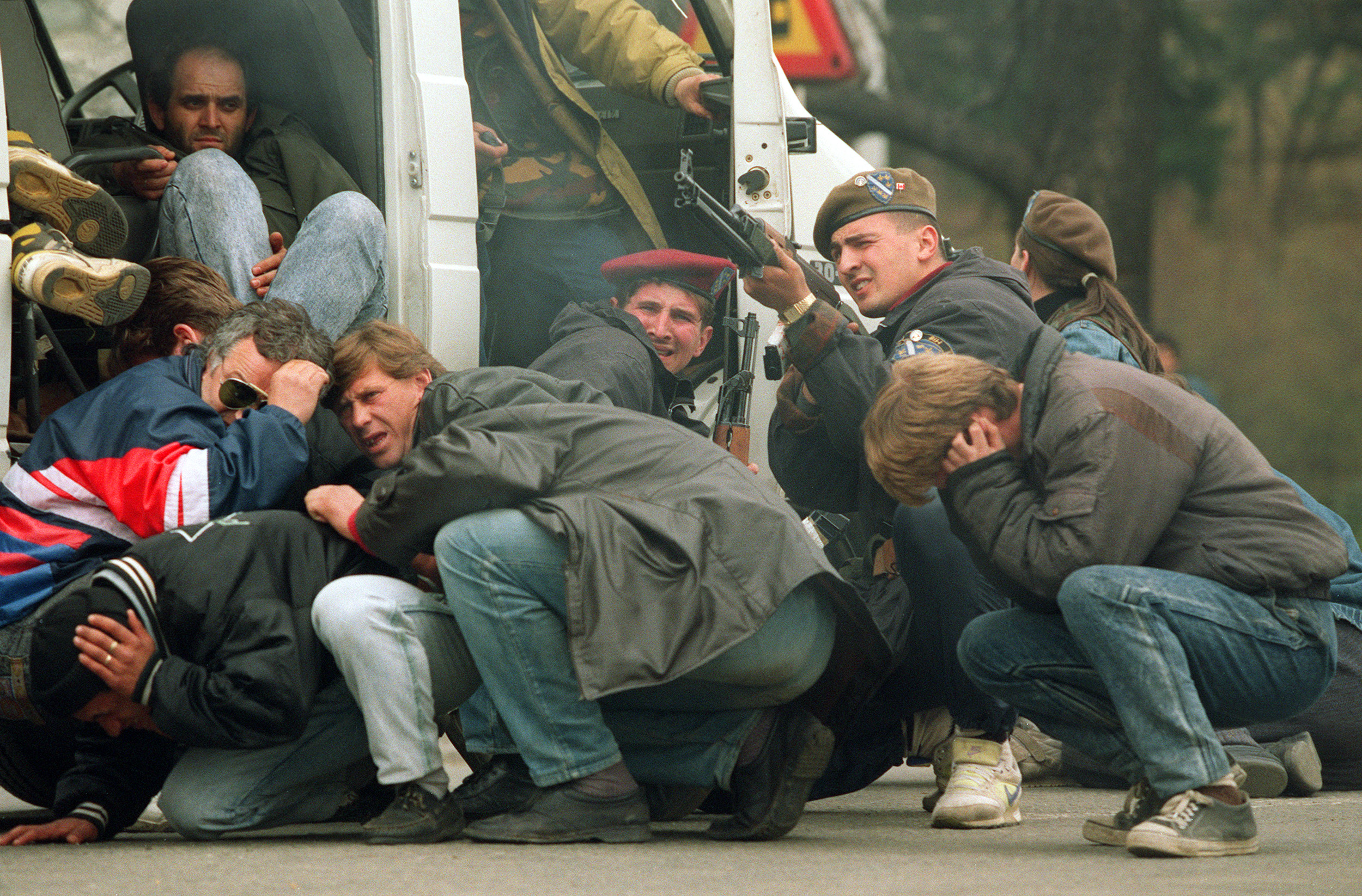 A Bosnian soldier in downtown Sarajevo returns fire as he and civilians are harassed by Serbian snipers on April 6, 1992.