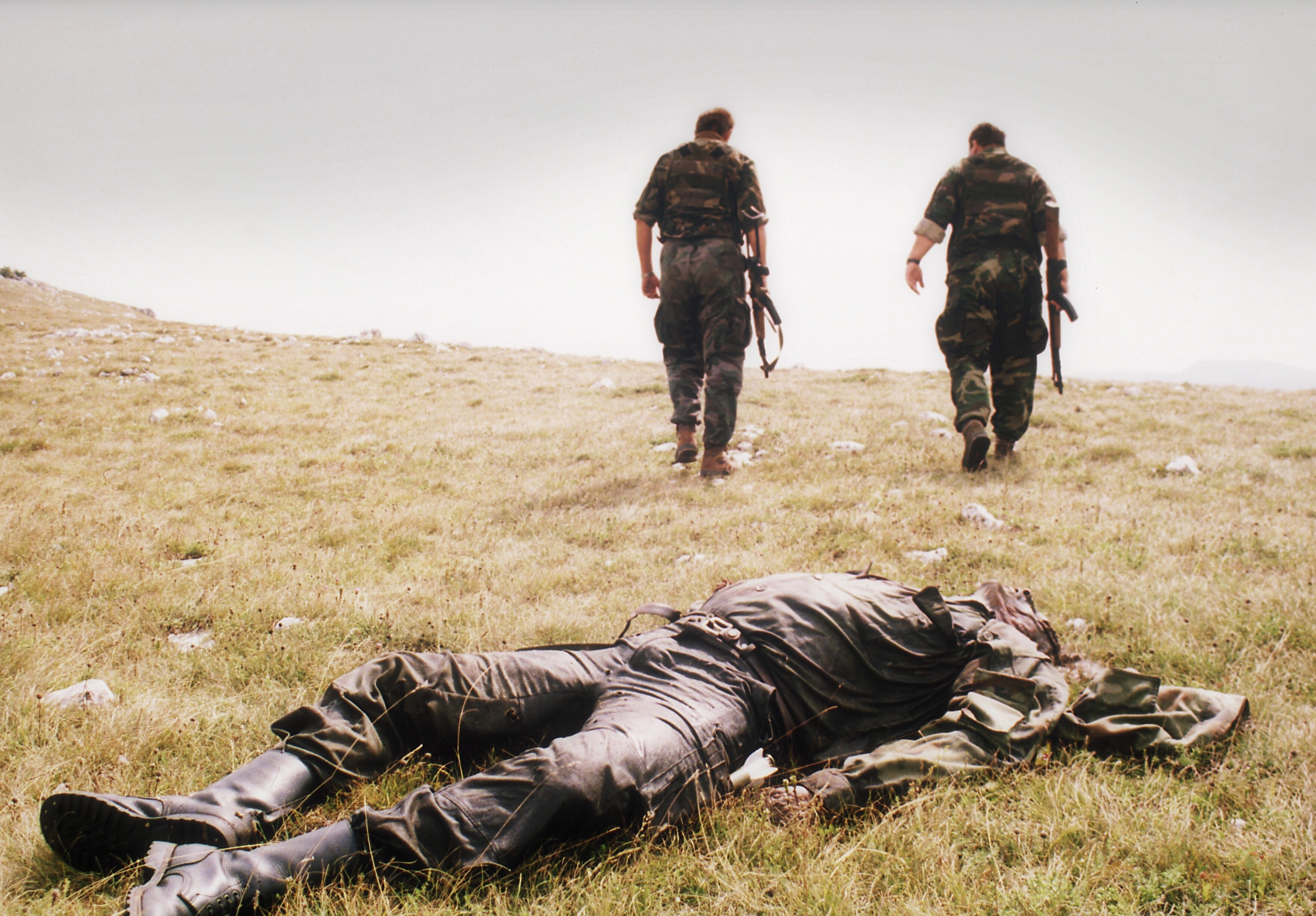 Two Bosnian Croat soldiers walk away from the corpse of a Bosnian Serb soldier killed in the Croatian attack on the Serb-held town of Drvar in western Bosnia, Aug. 18, 1995.