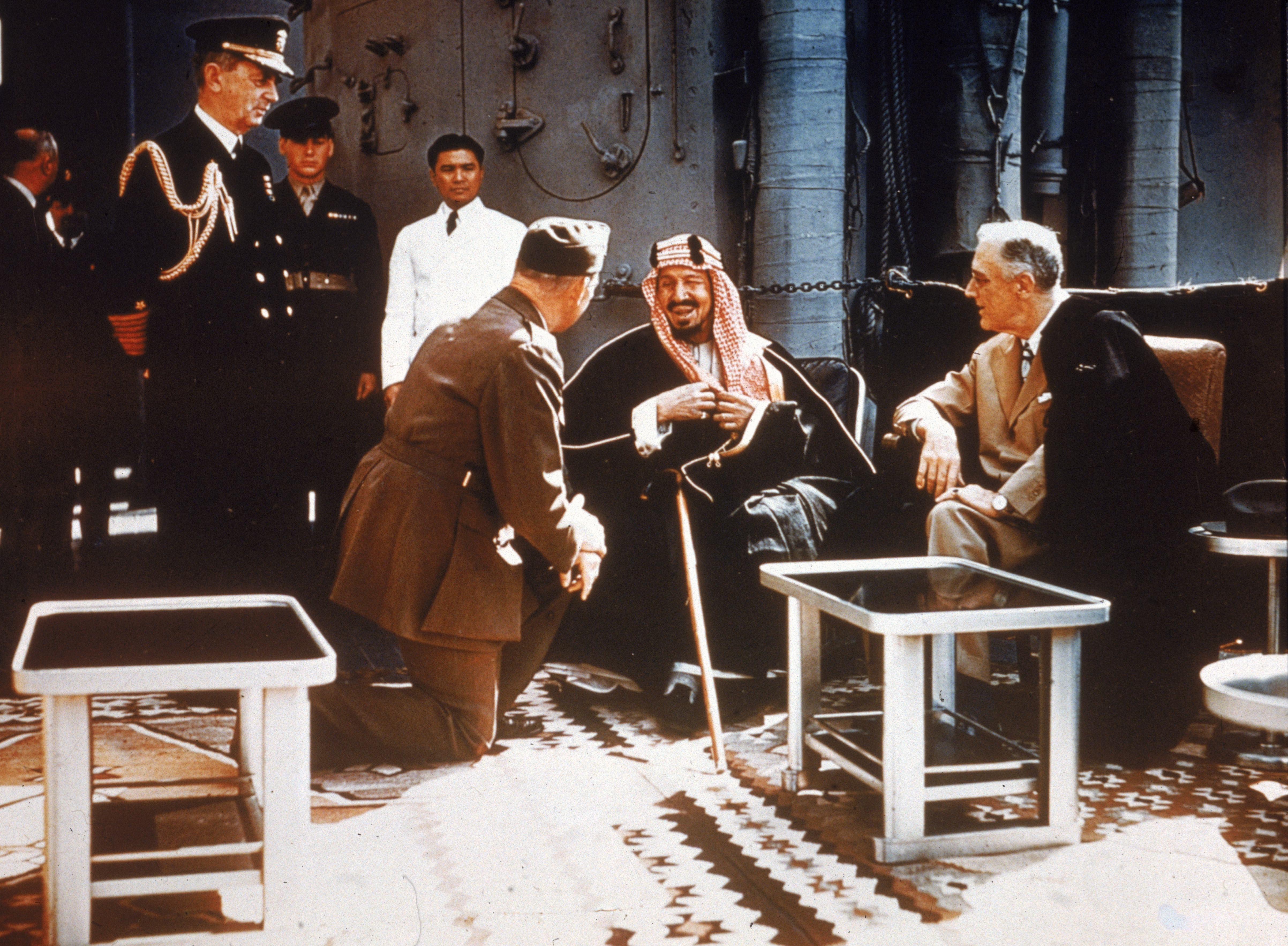 U.S. President Franklin Delano Roosevelt (right) meets with King Ibn Saud of Saudi Arabia, with chief of staff William D. Leahy (on knee) and minister to Saudi Arabia Col. William A. Eddy (to Leahy's right) aboard a U.S. warship on Feb. 20, 1945.