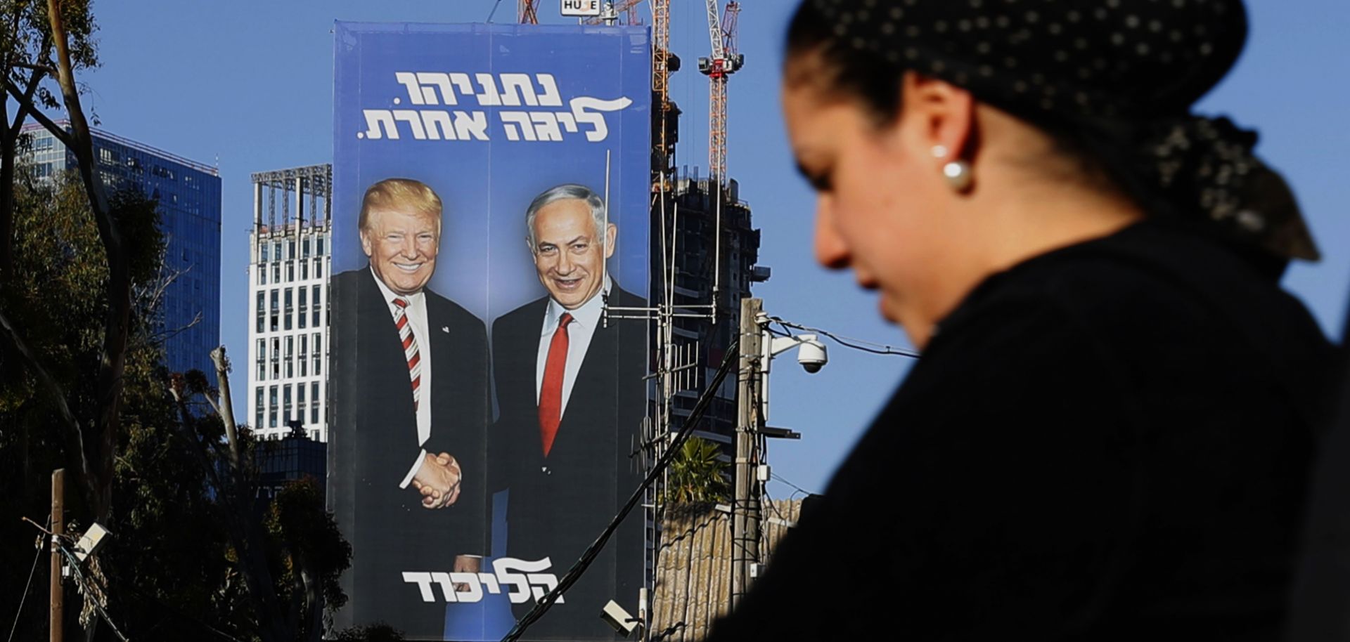 An election billboard in Tel Aviv on Feb. 3, 2019, shows Israeli Prime Minister Benjamin Netanyahu and U.S. President Donald Trump shaking hands. The Hebrew writing reads,