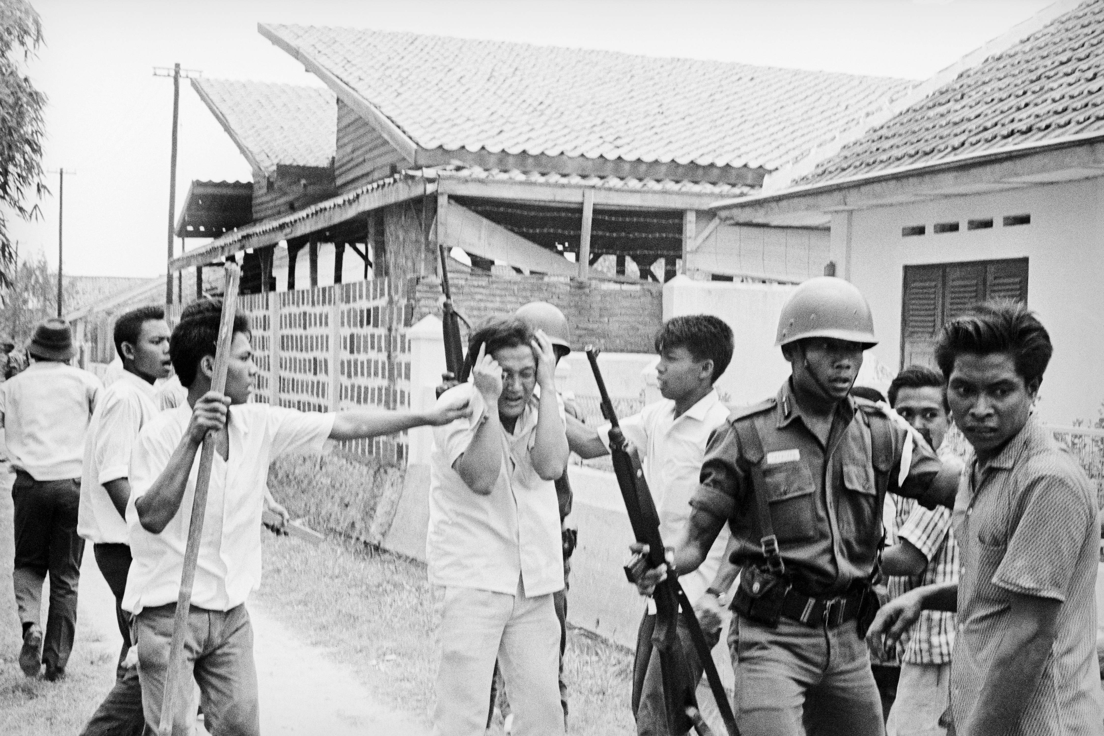 A picture of a Chinese student protecting himself as Indonesian youths attack him during the 1960s at the Republican University in the Indonesian capital.