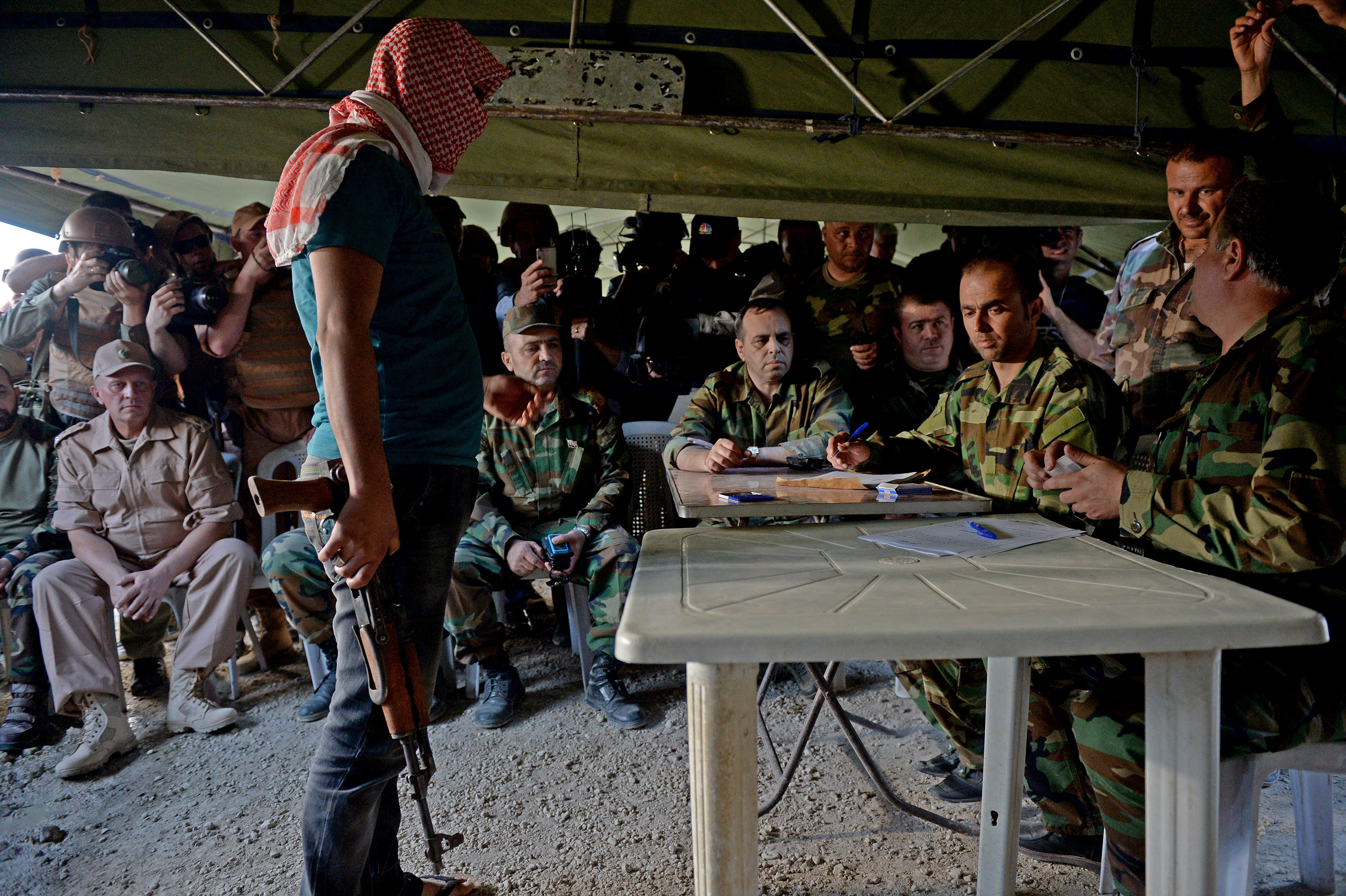 A former rebel fighter returns arms to a representative of the Syrian government accompanied by Russian military personnel in the village of Kawkab, near the city of Hama, on May 4, 2016.