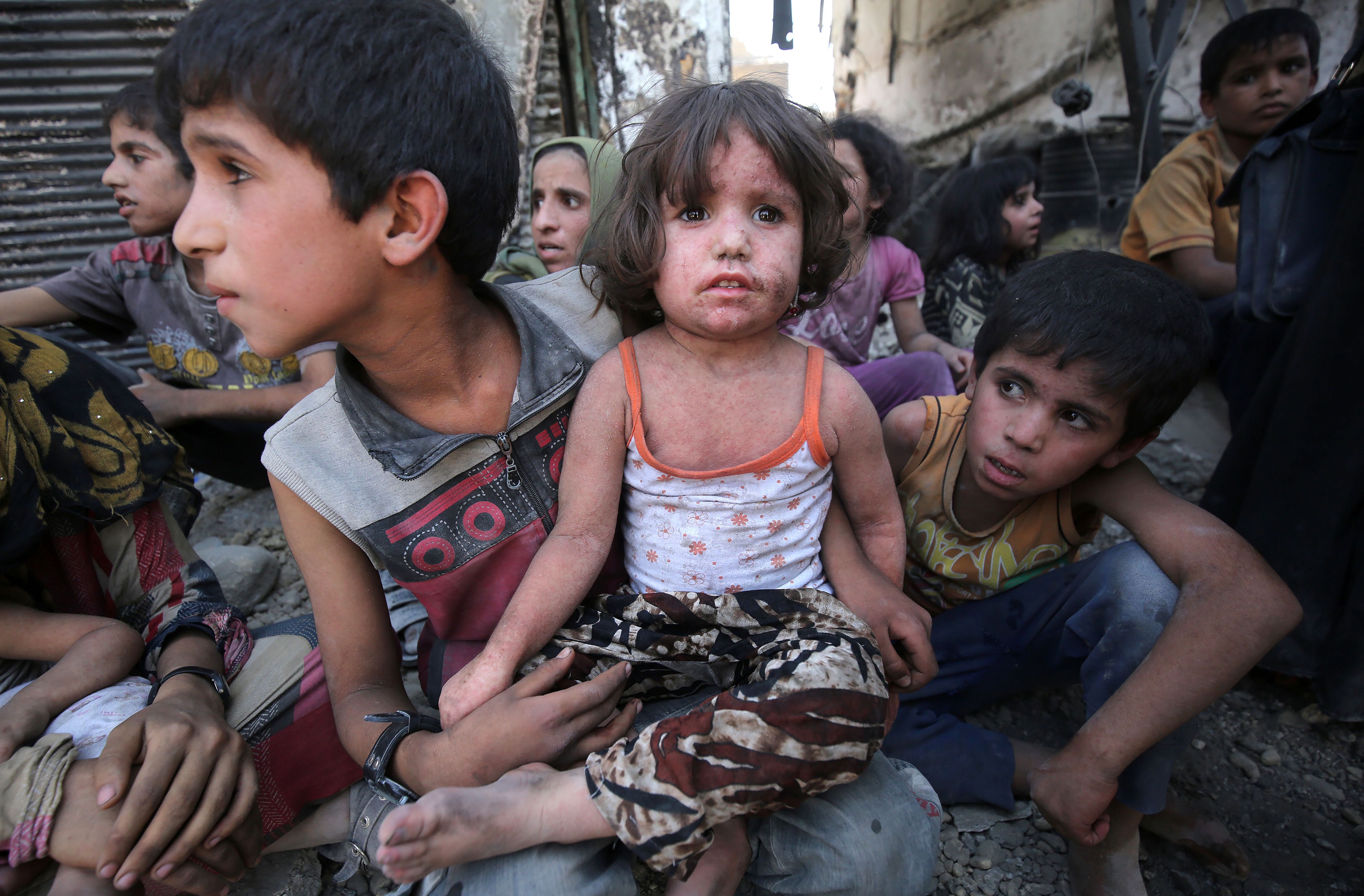 A young girl sits on a boy's lap as families wait for the fighting in Mosul's Old City to be over.