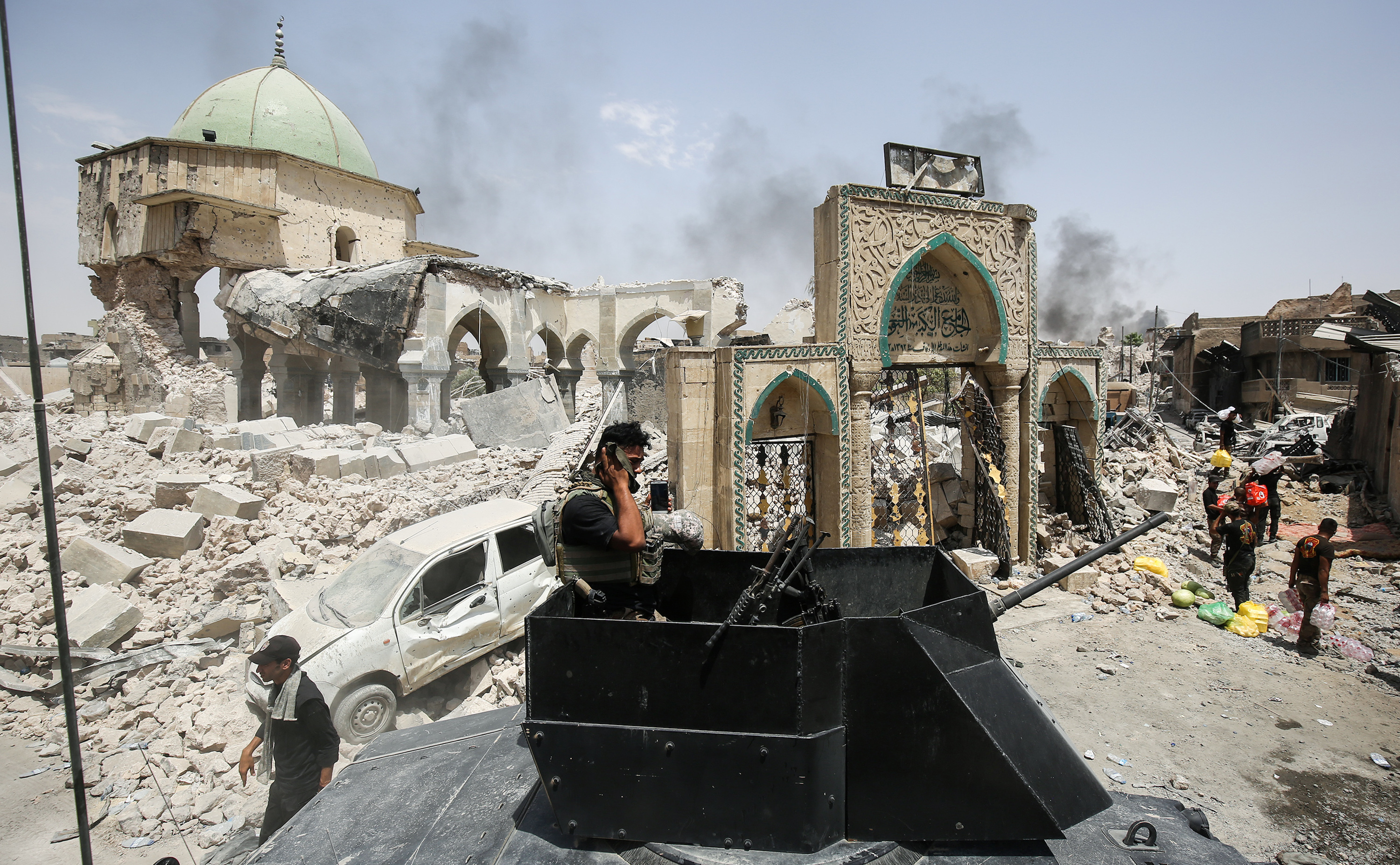 A member of the Iraqi Counter-Terrorism Service (CTS) wipes his face while standing in the turret of a up-armored vehicle parked outside the destroyed gate of Al-Nuri Mosque in the Old City on July 2. 