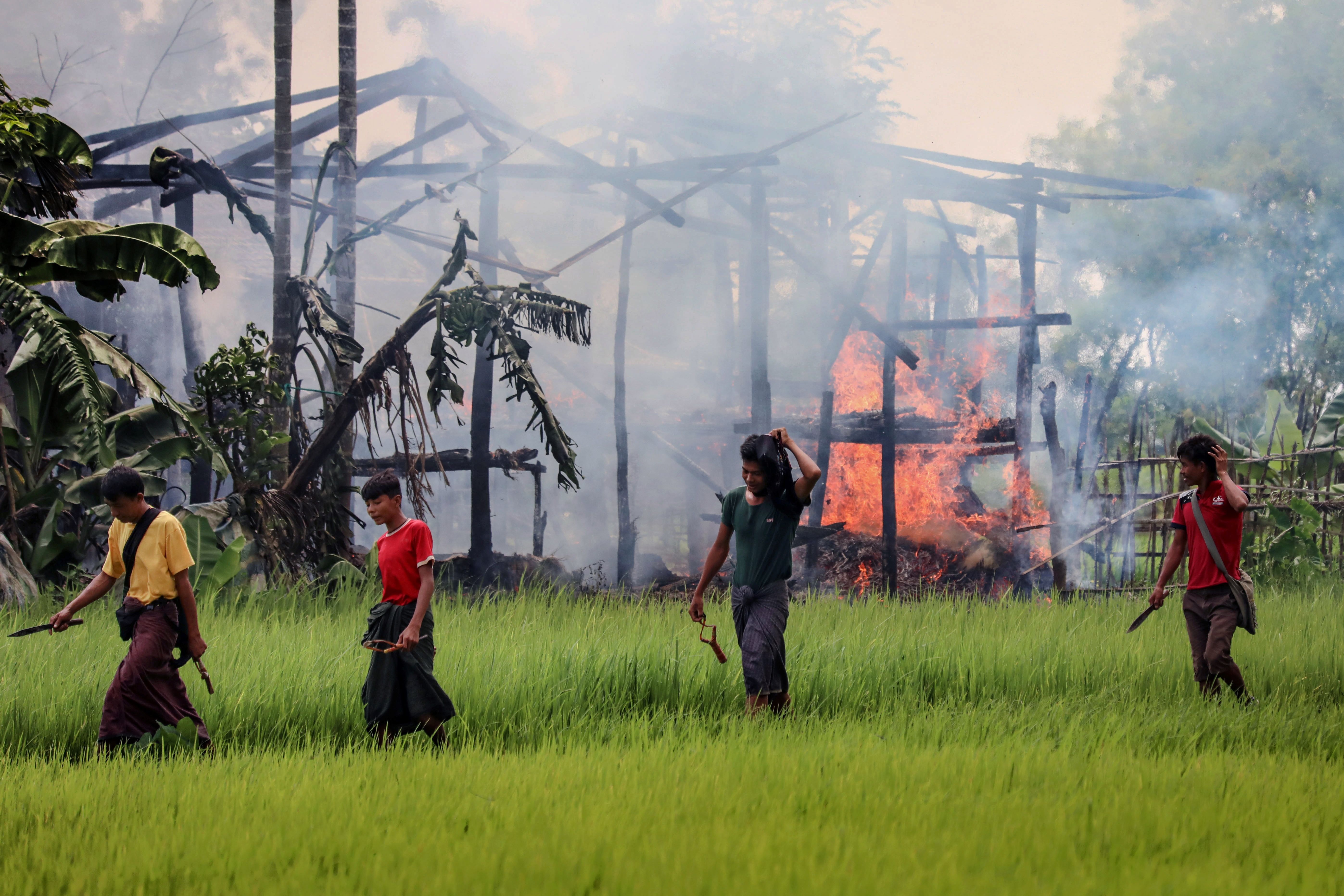 Rakhine Buddhists reportedly have burned thousands of Rohingya houses in western Rakhine state. Several young men walk past a burning structure on Sept. 7.