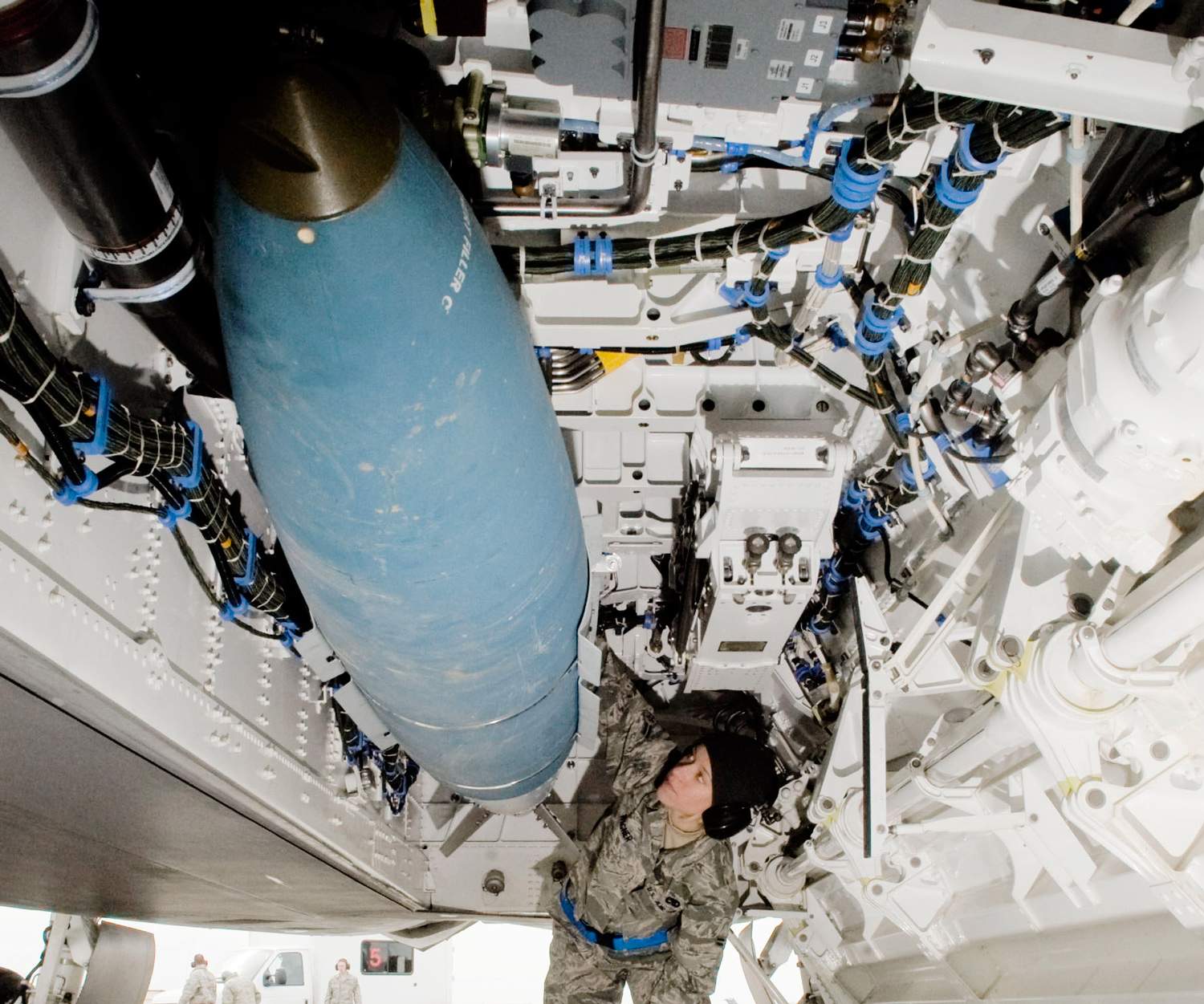A picture of an airman inspecting a Joint Direct Attack Munition being loaded onto an F-22 Raptor.