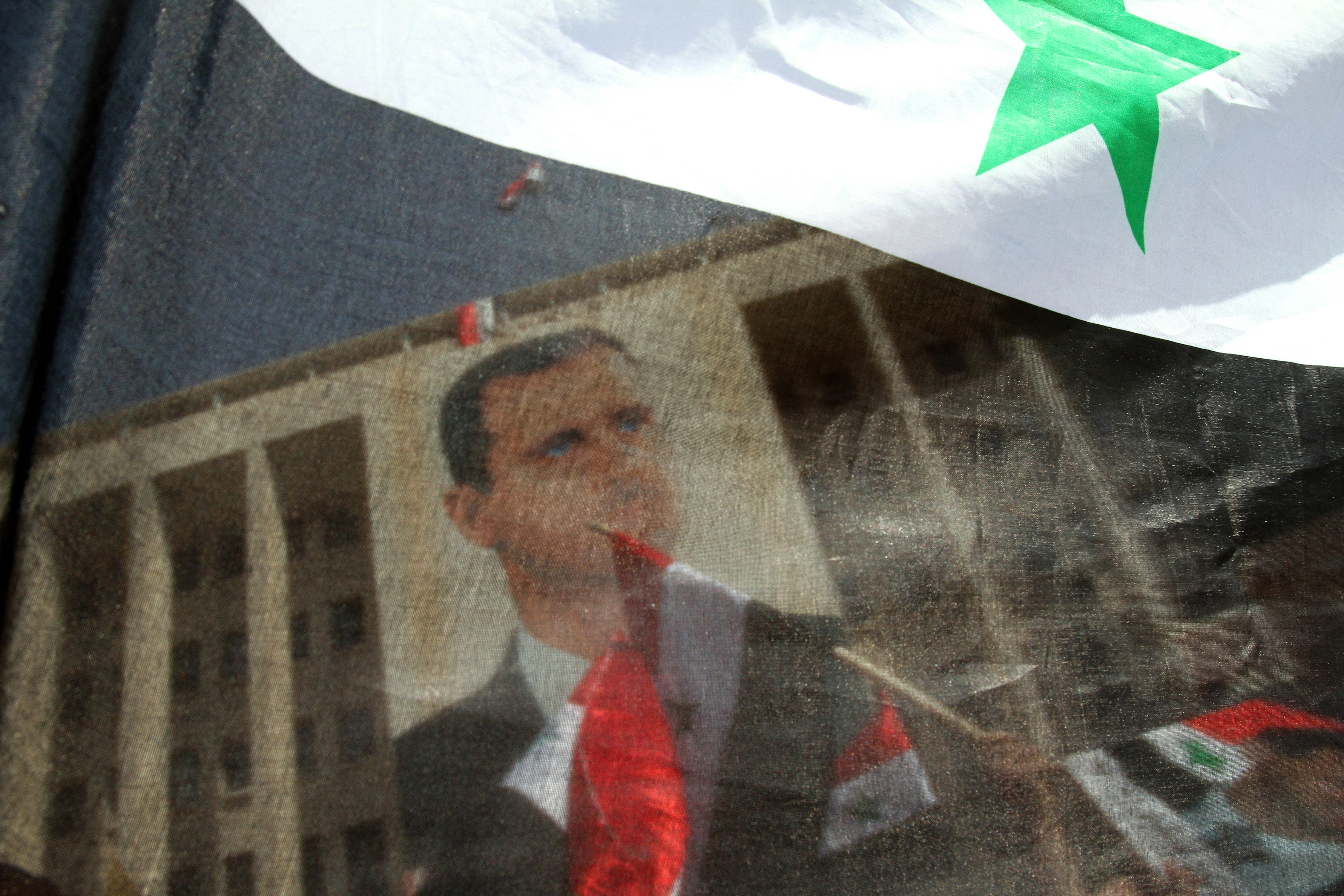 Syrians in Damascus on March 29, 2011, wave their national flag and hold portraits of President Bashar al Assad during a rally to show support for their leader in the wake of dissent.