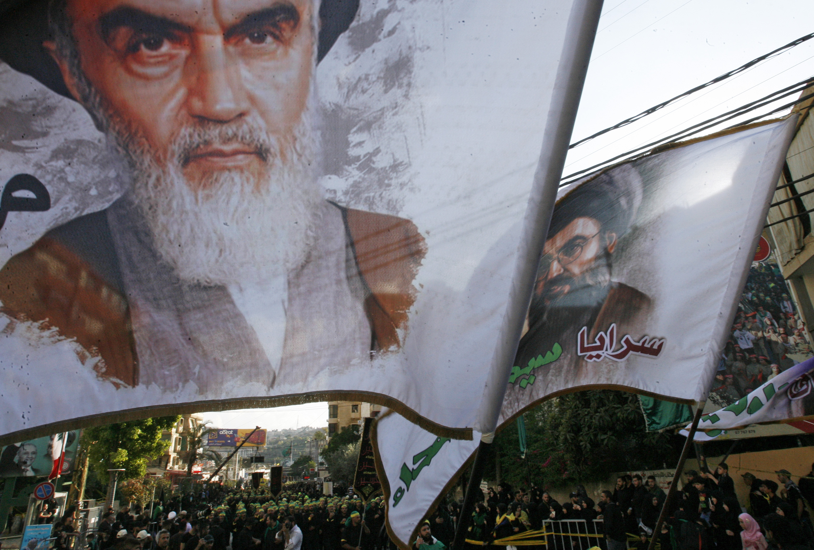 Supporters of Lebanon's Shiite Hezbollah militant group wave flags bearing portraits of former Supreme Leader Ayatollah Ruholla Khomeini (L) in the southern Lebanese city of Nabatieh on Oct. 4, 2017. 