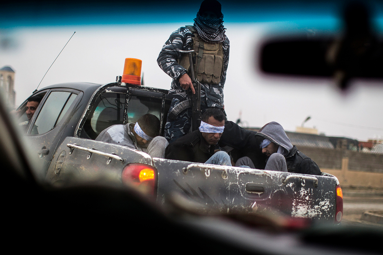 Christian militia fighters from the Nineveh Plain Protection Units drive a pickup truck in Qaraqosh, Iraq, transporting four alleged members of the Islamic State on Dec. 20, 2016.