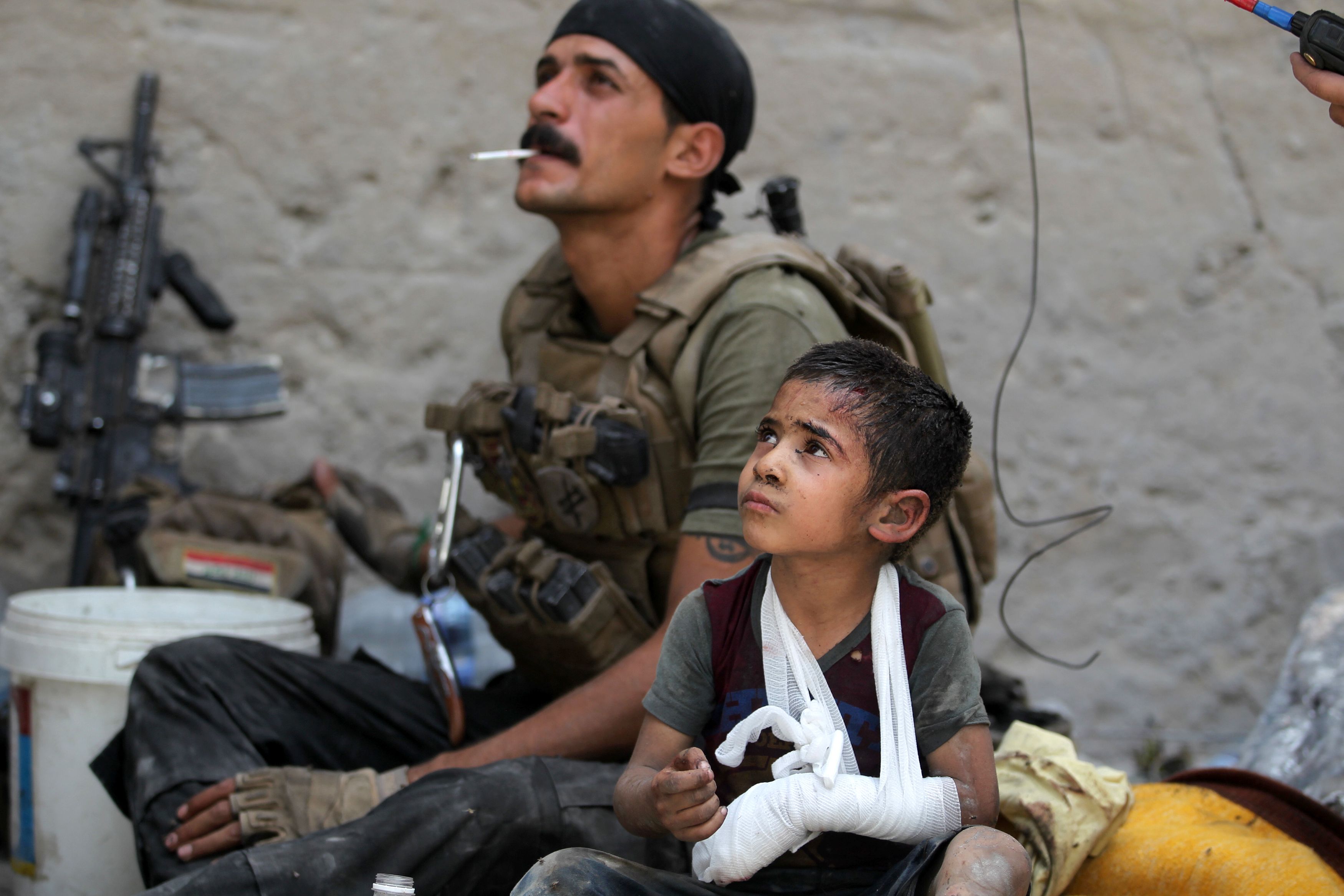 Omar, a young wounded Iraqi boy whose family was killed in the fighting, sits with members of the Counter Terrorism Service (CTS) as they help him escape the Old City, July 3. 2017.