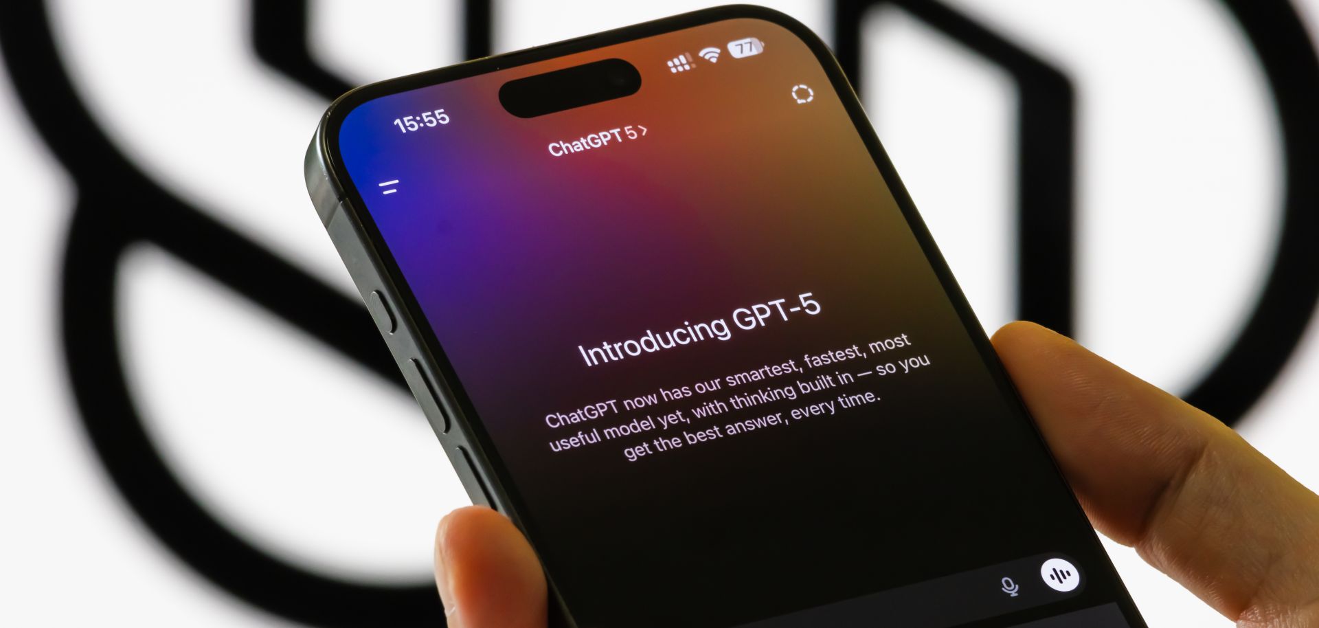 A person holds a smartphone showing an interface introducing OpenAI's new GPT-5 model in the ChatGPT app in front of a blurred OpenAI logo on Aug. 9, 2025, in Chongqing, China. 
