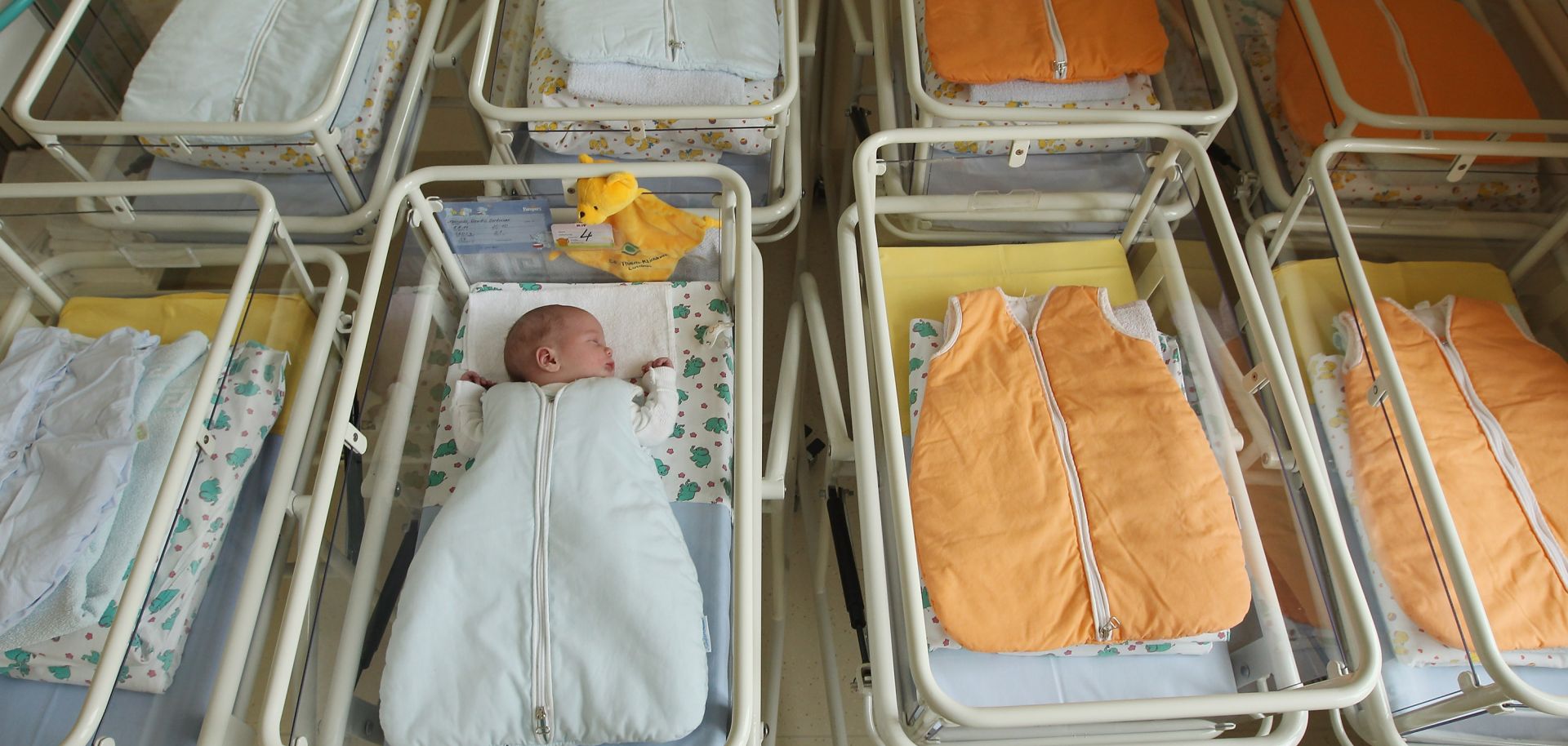 A 4-day-old newborn baby, who has been placed among empty baby beds in the maternity ward of a hospital.