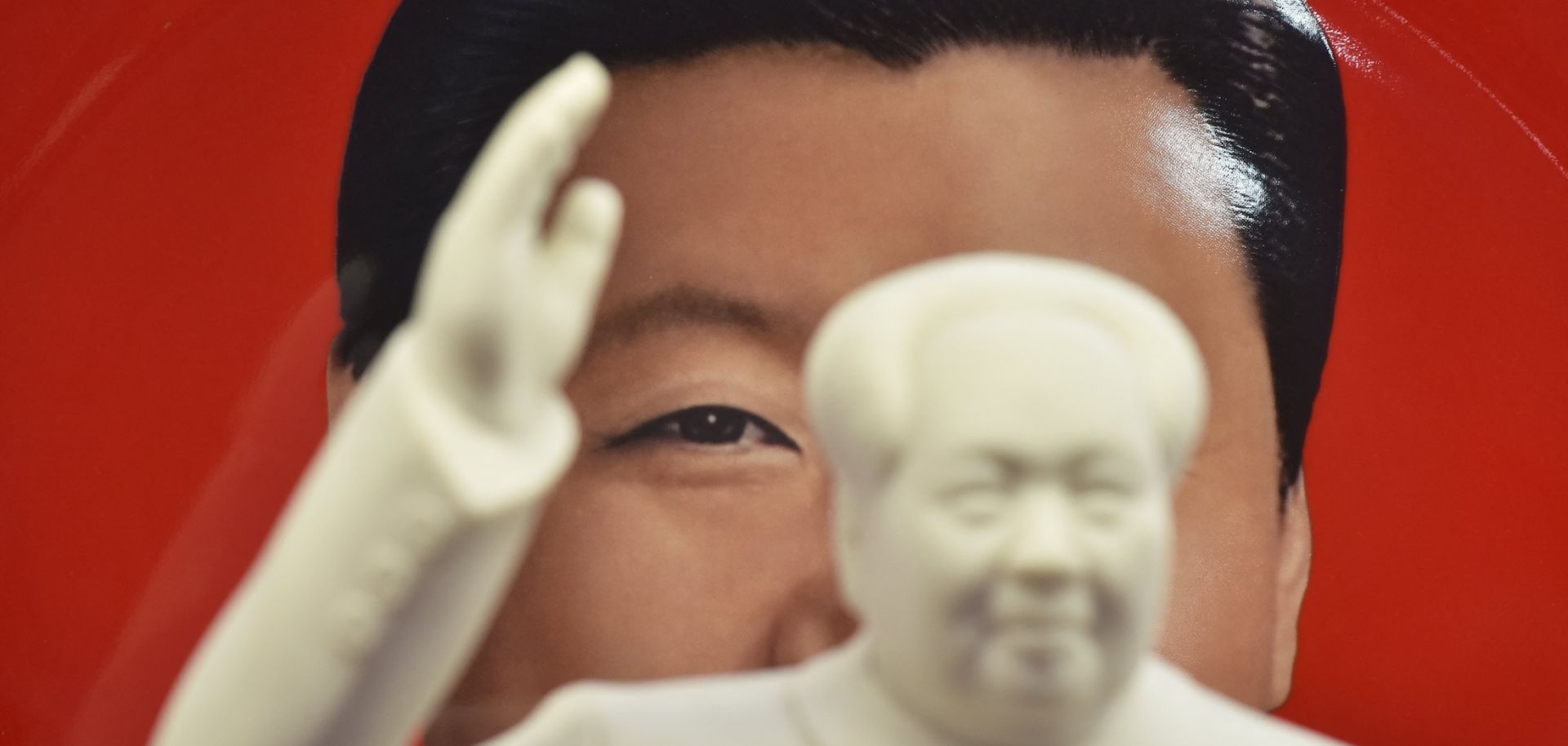 A decorative plate featuring an image of Chinese President Xi Jinping is seen behind a statue of late communist leader Mao Zedong at a souvenir store next to Tiananmen Square in Beijing, China, on Feb. 27, 2018.