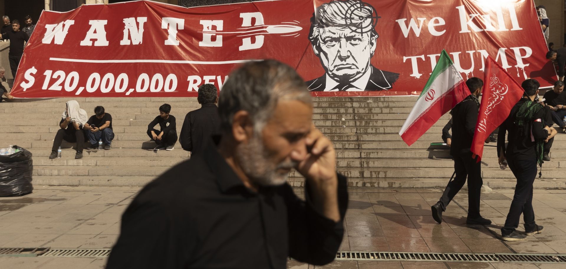 People pass a large banner depicting U.S. President Donald Trump with a target on his head during funeral ceremonies for Supreme Leade, Ayatollah Ali Khamenei on July 5 in Tehran, Iran. U.S.-Iran clashes will likely continue over the next week.