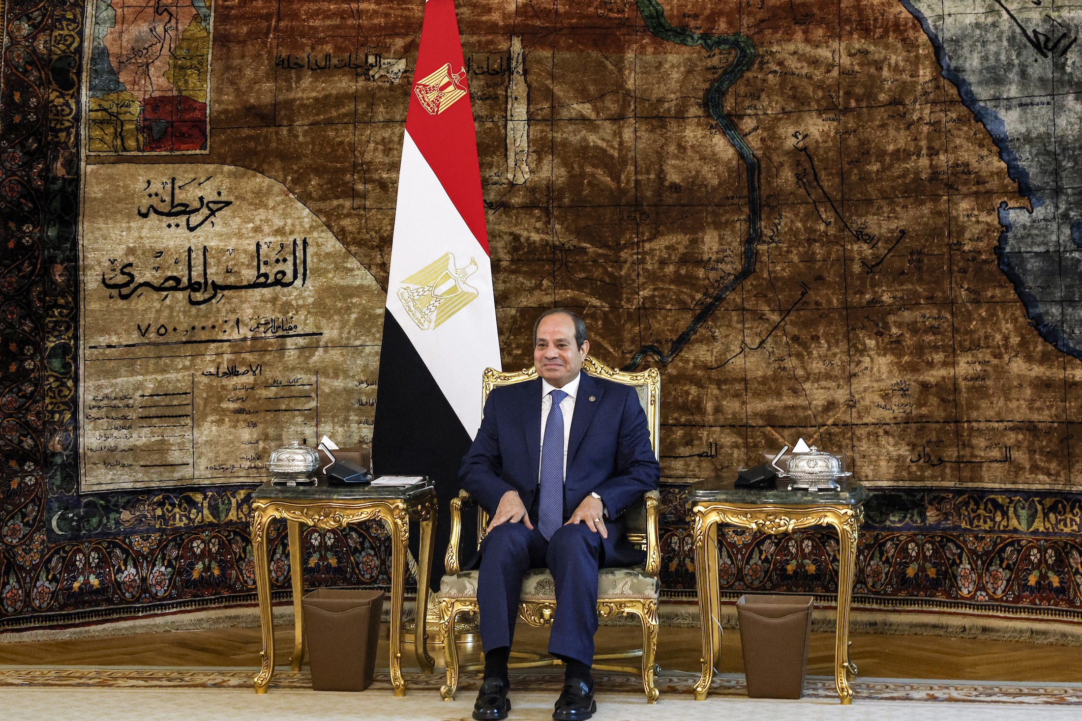 Egyptian President Abdel Fattah al-Sisi sits in a chair with the Egyptian flag behind him, looking on during a meeting at the presidential palace in Cairo on Sept. 18, 2024.